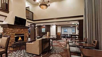 A hotel lobby with a fireplace, seating area, and a staircase.