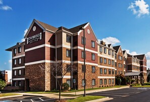 A Staybridge Suites hotel with a brick facade, multiple balconies, and a parking lot.