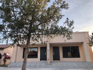 A modern building with a flat roof, large windows, and a tree in the foreground. - Plush 1Bed Apt PHI Great East Rd (Lusaka)