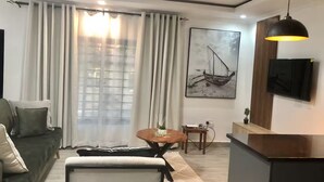 Una sala de estar moderna con sofá, mesa de comedor y televisor montado en la pared.
