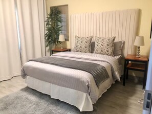 A neatly arranged bedroom with a bed, bedside tables, a lamp, and a potted plant. - Plush 1Bed Apt PHI Great East Rd (Lusaka)