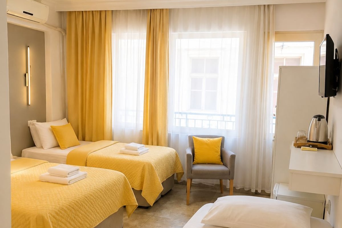 Una habitación de hotel con dos camas, una silla, un escritorio y un televisor.