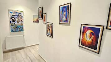 An art gallery with several framed paintings on the walls and a radiator on the left.