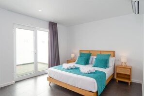 A modern hotel room with a large bed, two bedside tables, a sliding glass door, and a view of the outside. - Vacation Villa 'Ereza Royal Deluxe Hoopoe 104' with Mountain View, Private Pool and Wi-Fi (Playa Blanca)