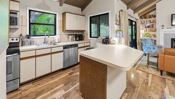 A modern kitchen with wooden cabinets, a dishwasher, and a large island.