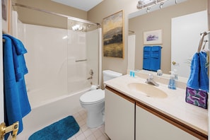 A bathroom with a bathtub, toilet, sink, and a shower area.