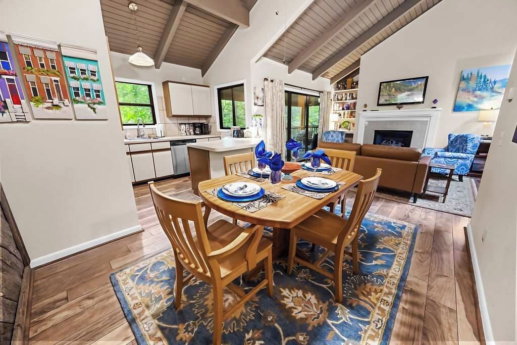 A dining area with a wooden table, chairs, and a blue patterned rug.