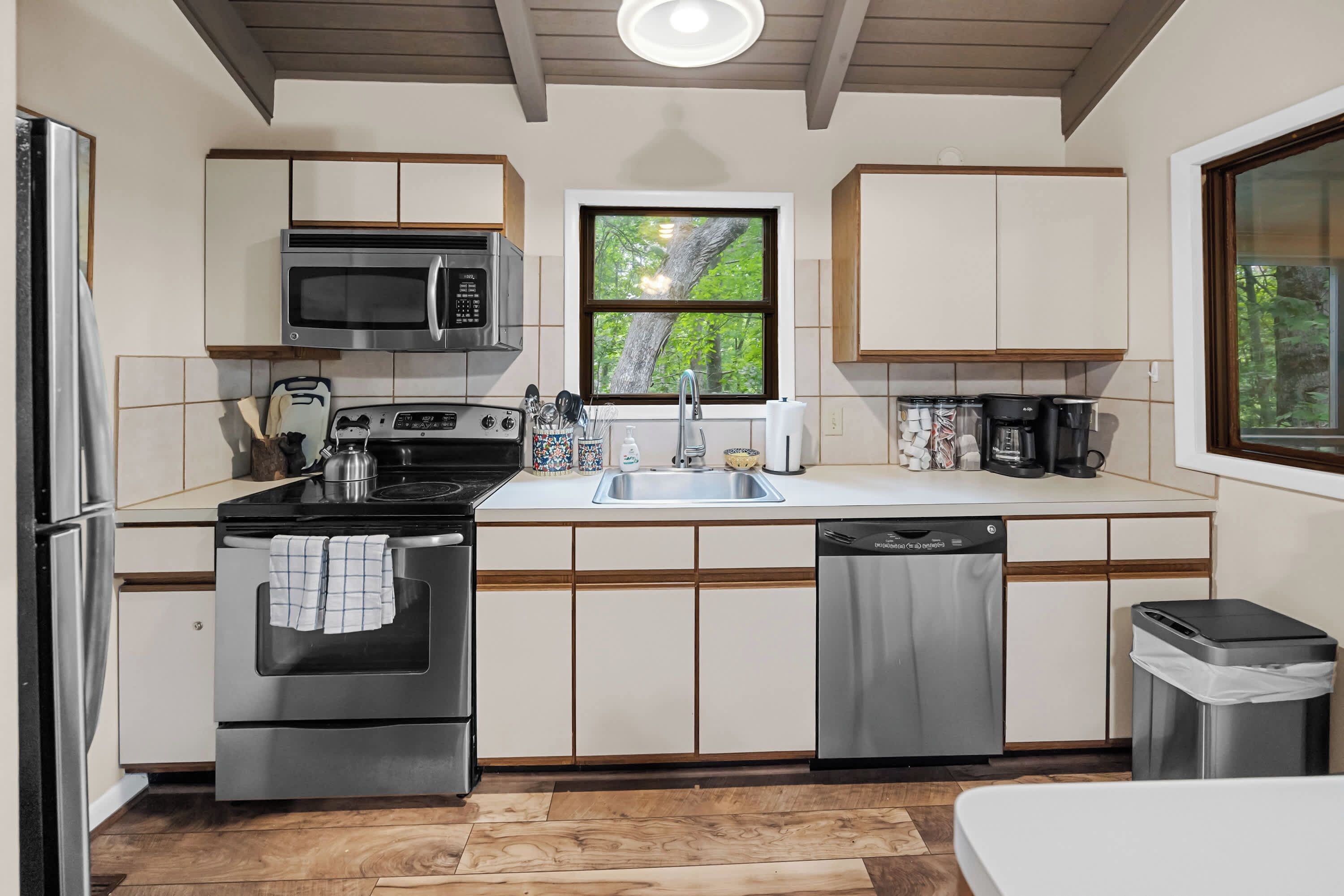 A compact kitchen with a microwave, stove, sink, and dishwasher.