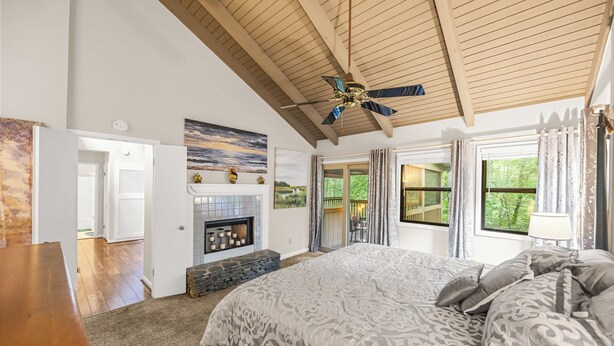Quarto com cama grande, lareira, ventoinha no teto e vista para o exterior.