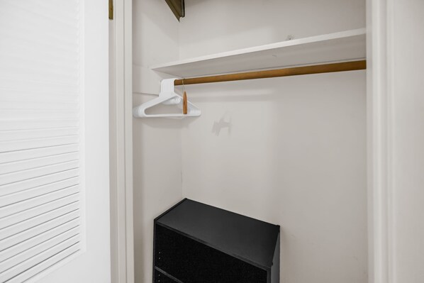 A closet with a wooden rod, a white hanger, and a black storage unit.