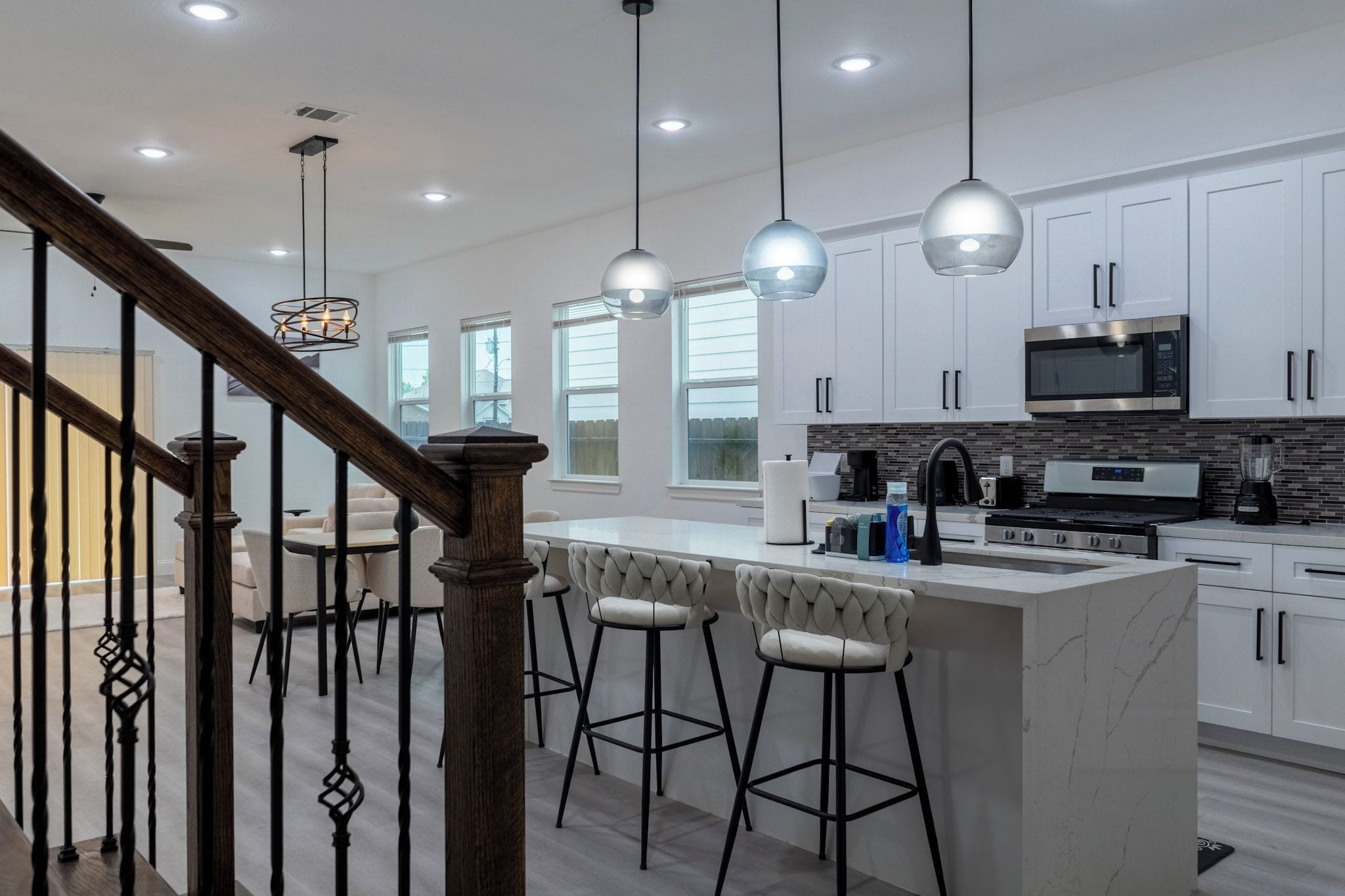 A modern kitchen with a central island, bar stools, and a stainless steel microwave.