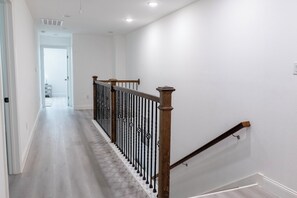 En stilren, modern hall med en trappa i trä och en vit vägg.