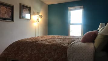 Une chambre à coucher avec un lit, une lampe sur pied et une fenêtre.