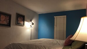 Une chambre à coucher avec un lit, une lampe et deux tableaux encadrés accrochés au mur.