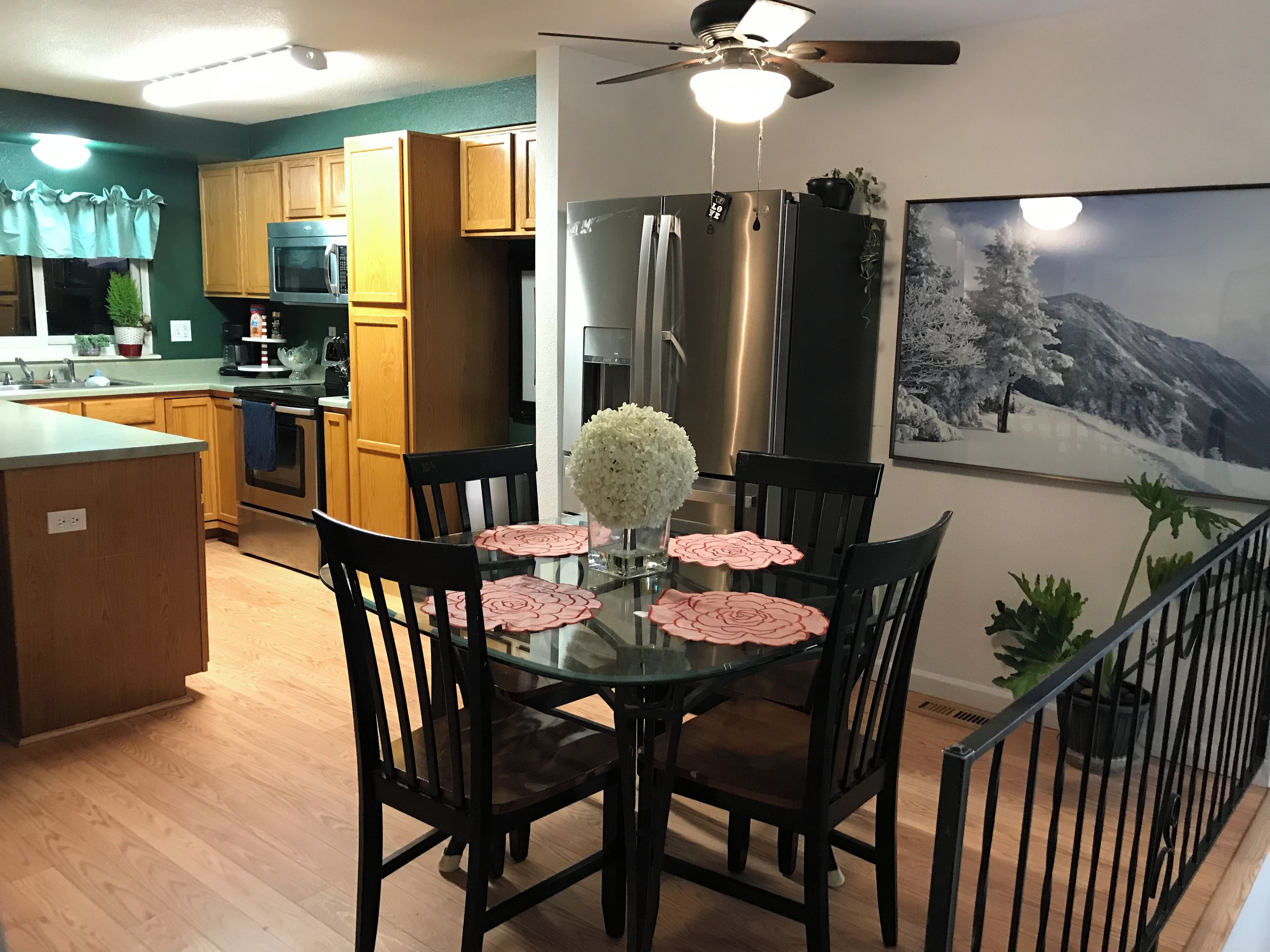 A modern kitchen with wooden cabinets, stainless steel appliances, and a dining area with a glass table and chairs.