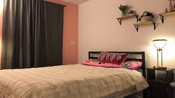 Una camera da letto con un letto, un comodino, una lampada, una finestra con tende e mensole a parete.
