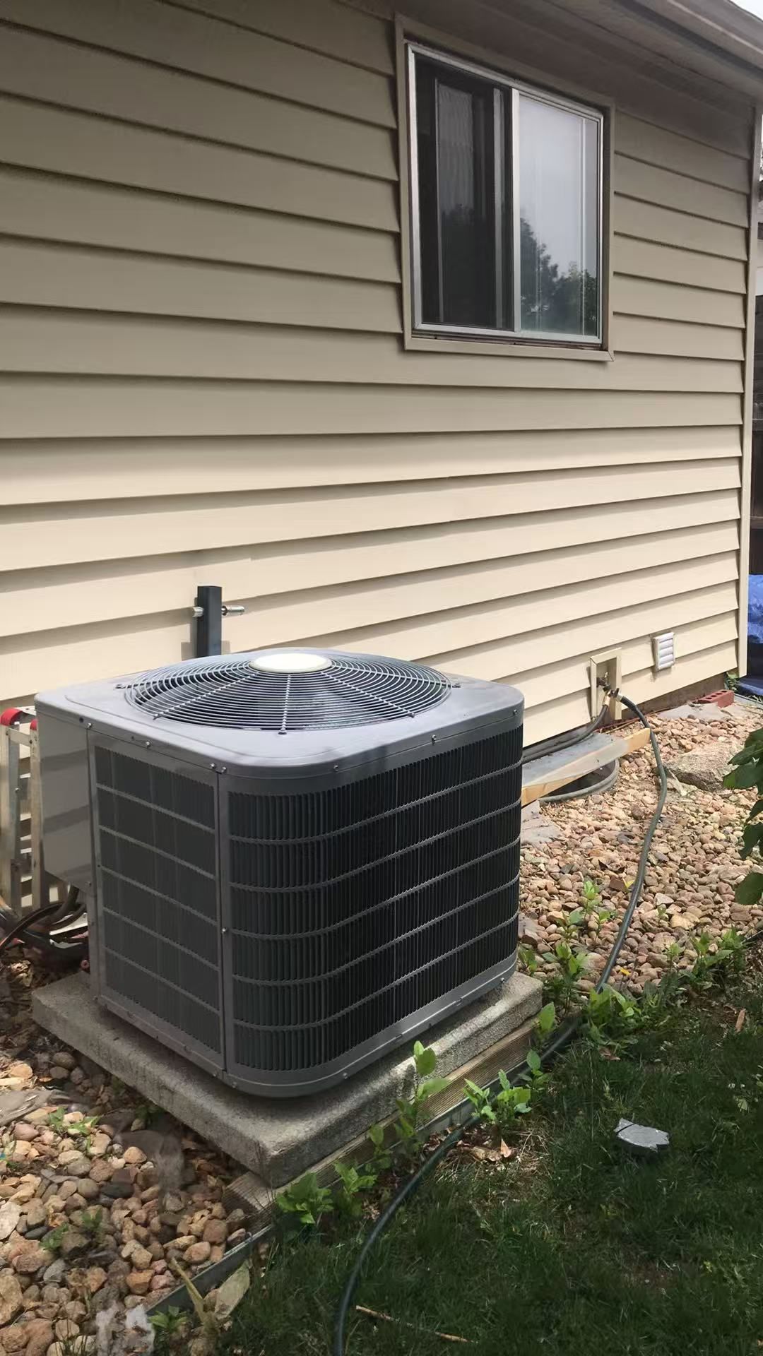 Un appareil de climatisation extérieur installé sur le mur extérieur d’une maison.