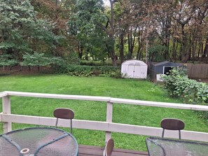 Un pati amb un terra de fusta, dues cadires, un cobert i un jardí.