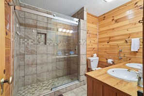 Un bagno con doccia vetrata, un mobile lavabo in legno e un water.