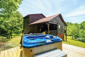 A wooden cabin with a hot tub on a wooden deck.