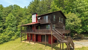 A two-story log cabin with a balcony and a staircase leading to the upper level. - LeVasseur Cabin  Simple Escape (Murphy)