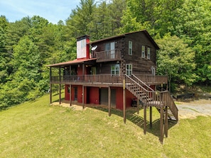 Eine zweistöckige Blockhütte mit einem Balkon und einer Treppe, die zum Obergeschoss führt.