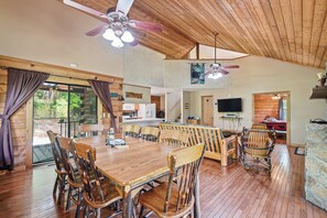 Ein geräumiges Ferienhäuschen-Interieur mit großem Esstisch, mehreren Stühlen, Deckenventilatoren und einer Küchenzeile.