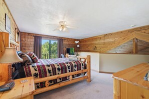 Ein gemütliches Schlafzimmer mit einem hölzernen Bett, einem Schreibtisch und einem Deckenventilator.
