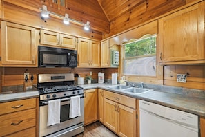 A kitchen with wooden cabinets, a stove, microwave, and a dishwasher. - Hanging Out in the Clouds (Blue Ridge)