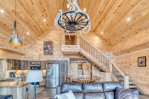 Geräumiges Cabin-Interieur mit Holzvertäfelung, einer Essecke, einem Wohnbereich mit Ledersofa und einer Treppe.
