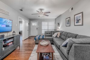 A living room with a gray sofa, a coffee table, a TV, and a ceiling fan. - Perfect 3-bedroom house w/ Smart TV, Patio, in peaceful Dallas neighborhood (Dallas)