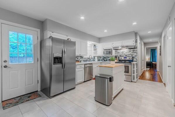 Una cocina moderna con electrodomésticos de acero inoxidable, armarios blancos y salpicadero de azulejos.