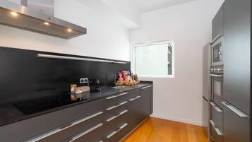 Una cocina moderna con encimera negra, electrodomésticos de acero inoxidable y una ventana que proporciona luz natural.