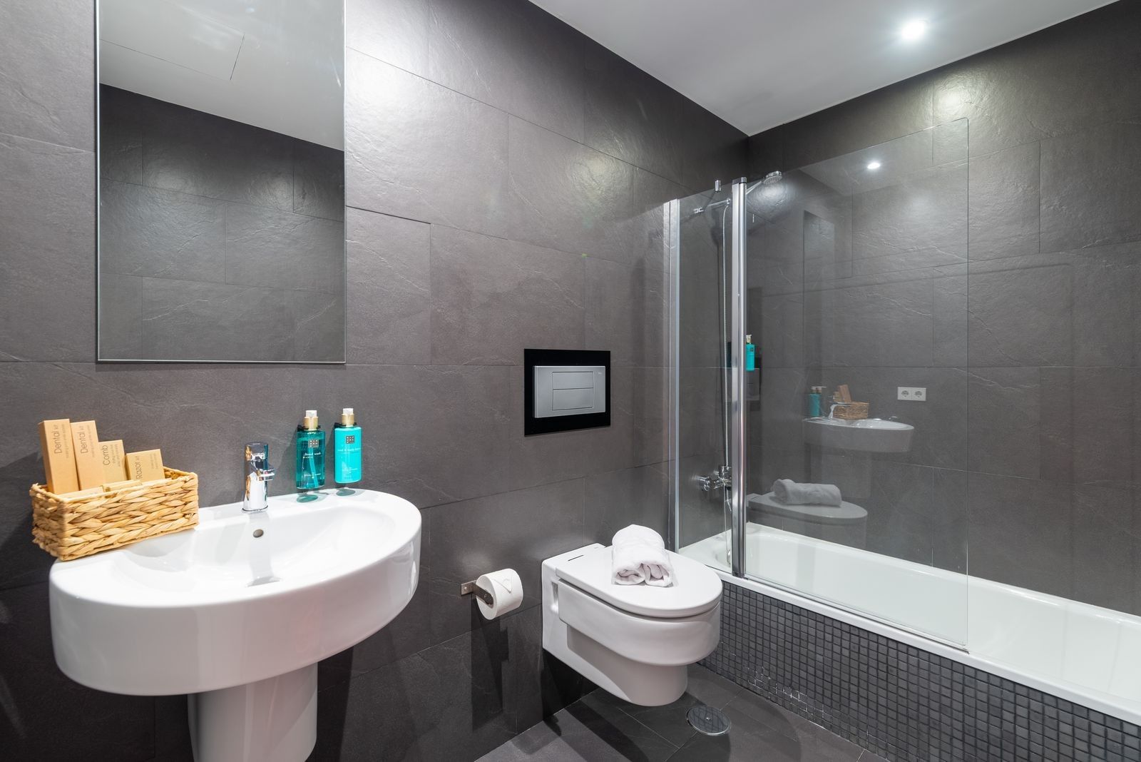 Un baño moderno con un lavabo blanco, cabina de ducha con mampara de cristal y un inodoro.