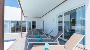 Un espace de détente extérieur moderne, doté de chaises longues et d’une piscine.
