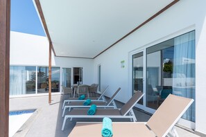 Uma área de estar ao ar livre moderna com espreguiçadeiras e piscina.