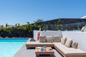 Ein Poolbereich mit einer Couch und einem Couchtisch, einem Rettungsring und freiem Blick auf den Pool.