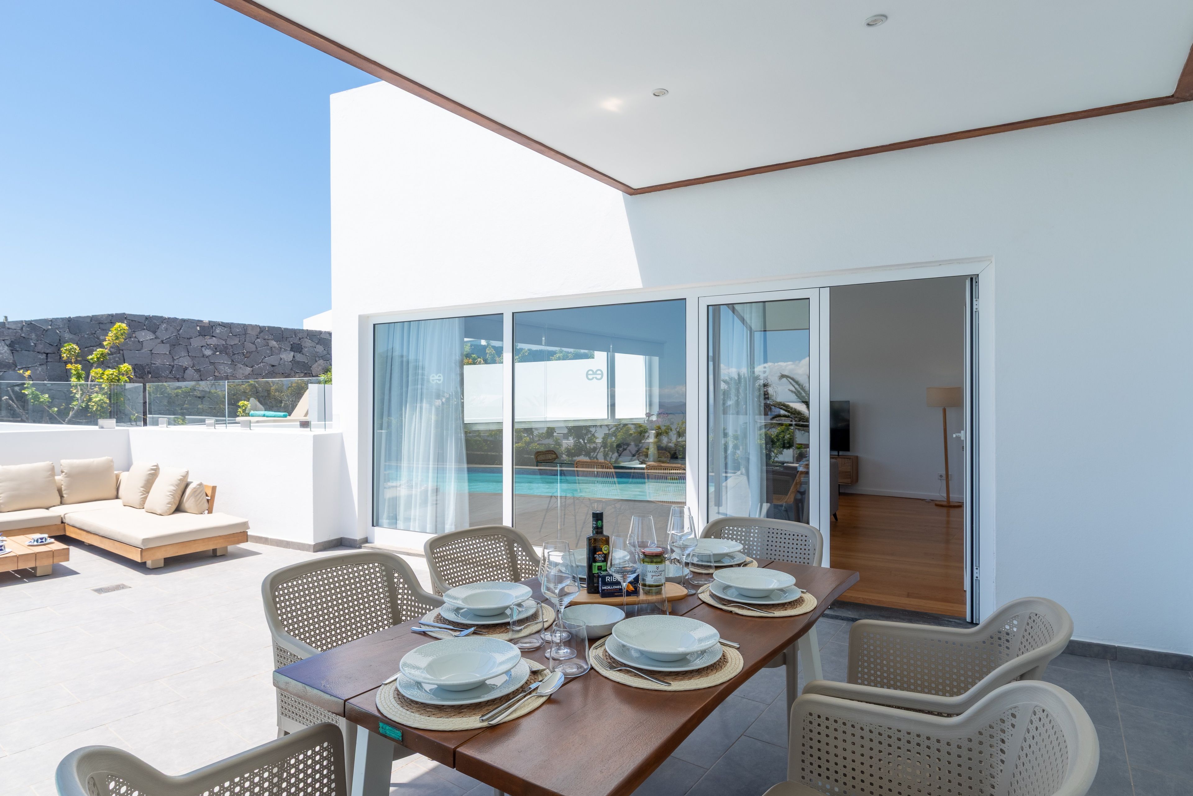 Ein Essbereich mit einem Tisch für vier Personen, mit Blick auf einen Swimmingpool und eine Berglandschaft.