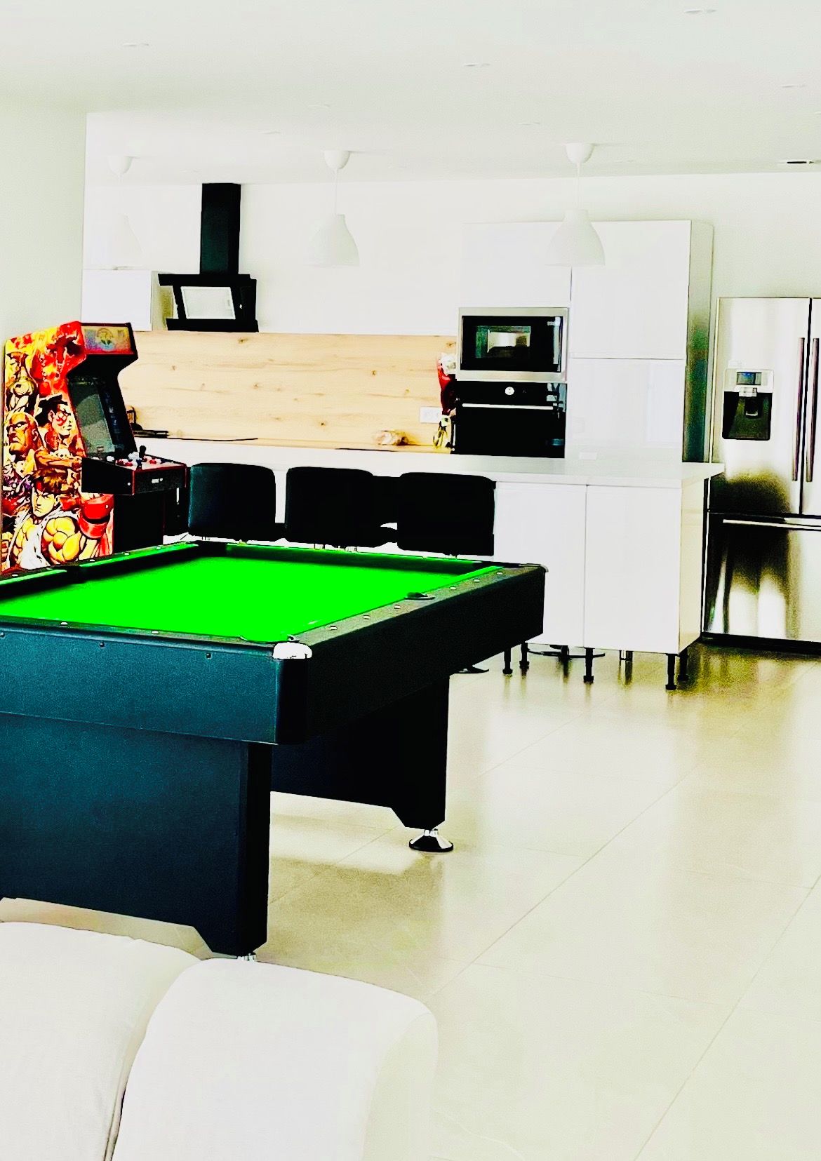 A pool table in a modern room with a kitchen area in the background.
