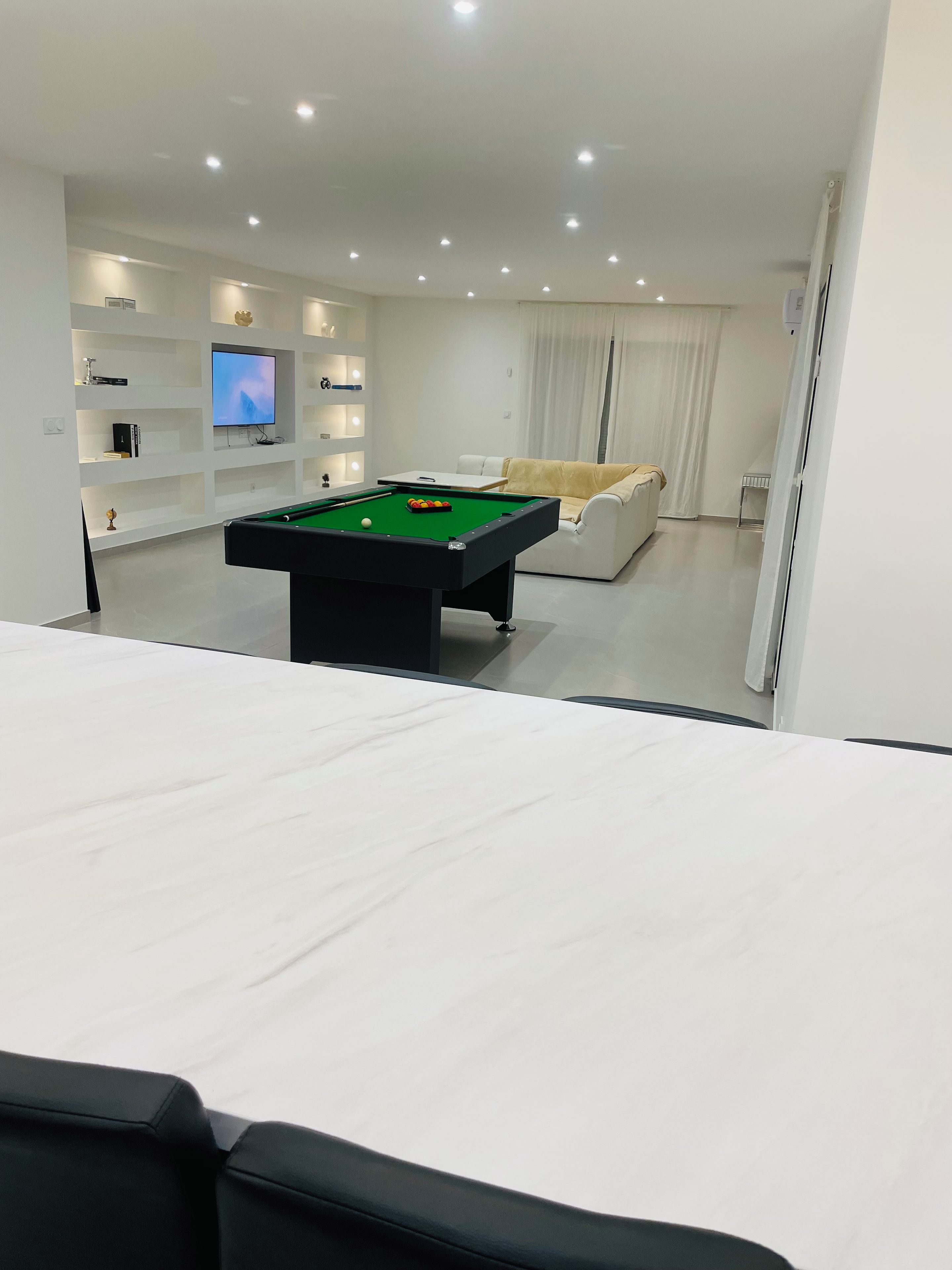 Una sala de estar moderna con mesa de billar, un sofá y una televisión.