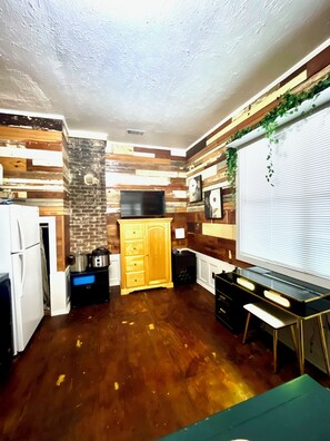 A compact kitchen with a refrigerator, stove, and wooden wall paneling. - Charming Vintage Loft in Bishop Arts (Dallas)