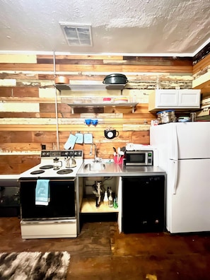 A compact kitchen with a stove, sink, microwave, and refrigerator. - Charming Vintage Loft in Bishop Arts (Dallas)