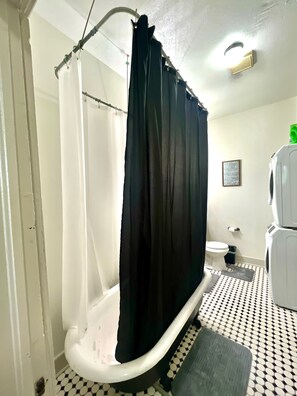 Een badkamer met een bad, toilet en douchegordijn.