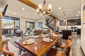 A spacious living area with a large wooden dining table, comfortable seating, and a view of the outdoors. - NEW! The Alders - Walk 2 Ski, Hot Tub, Fireplace (Dillon)