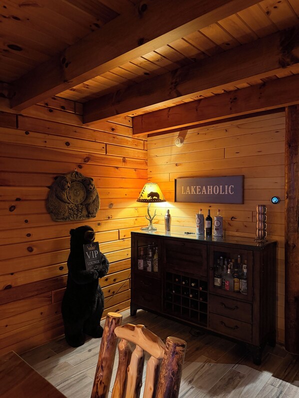 A wooden interior with a clock, a sign reading 'LAKEAHOLIC,' and a cabinet with bottles.