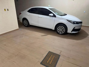 A white car parked in a room with wooden flooring and a doormat. - Pousada SMART AIRPORT 10min (Guarulhos)