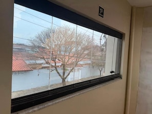 A window with a view of buildings and trees. - Pousada SMART AIRPORT 10min (Guarulhos)
