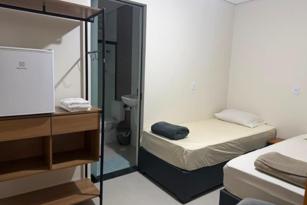 A compact hotel room with a bed, a small desk, a wardrobe, and a bathroom.