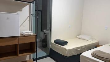 Habitación de hotel compacta con cama, escritorio pequeño, armario y baño.