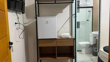 Un baño pequeño con zona de ducha, inodoro y lavamanos.